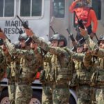 Mexican soldiers in camouflage uniforms raise weapons during a military parade in Colima, Mexico.