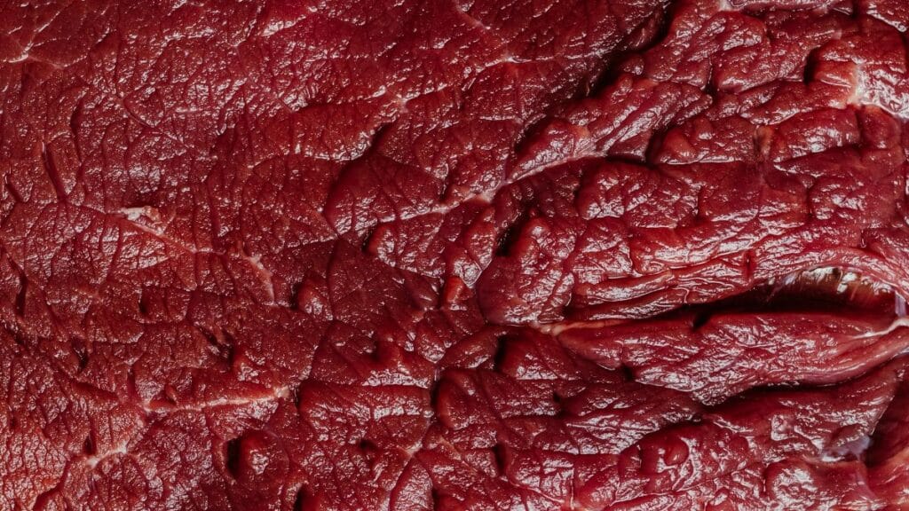 Detailed close-up of raw beef meat showcasing its rich texture and marbling.