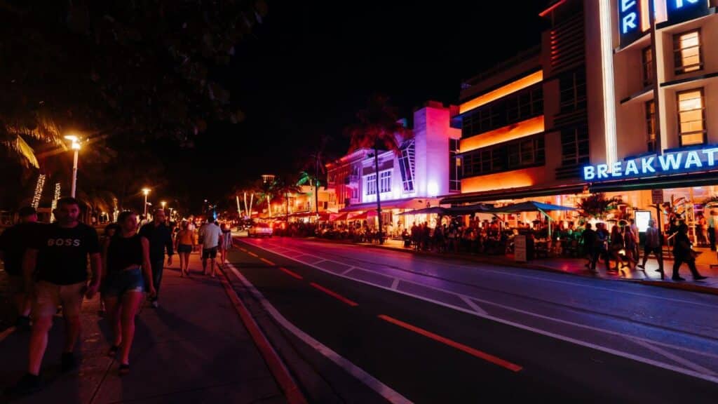 Explore the vibrant nightlife with neon lights and crowded streets on Miami's famous Ocean Drive.