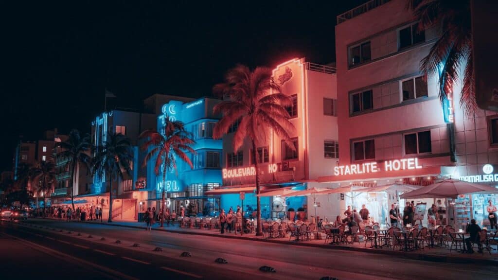 Colorful Art Deco hotels and lively street scene on Ocean Drive at night in Miami Beach.