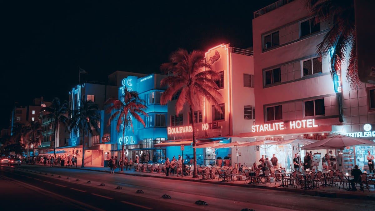 Colorful Art Deco hotels and lively street scene on Ocean Drive at night in Miami Beach.
