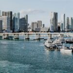 A scenic view of Miami skyline and marina, showcasing luxury yachts and modern skyscrapers under a clear blue sky.