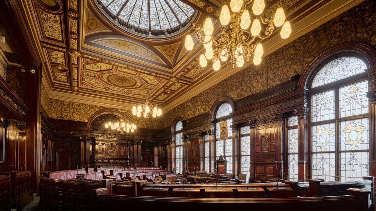 Elegant interior of Glasgow City Chambers featuring intricate details and stained glass windows.