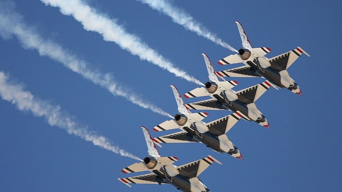 Four fighter jets performing a precise aerial formation with vapor trails against a clear blue sky.