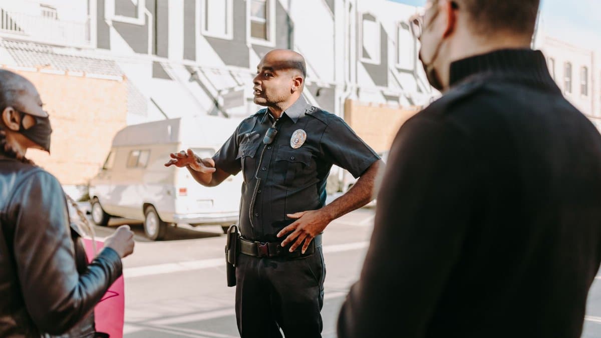 A police officer interacting with civilians during a peaceful protest in an urban setting.