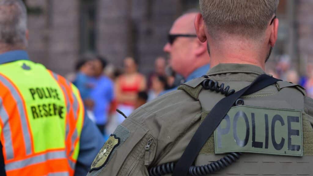 Police officers maintaining security at a public event with a crowd in the background.