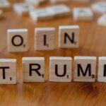 Scrabble tiles spelling 'TRUMP' on a wooden table, creating a political theme.