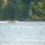 A speed boat cruising on the Mississippi River near wooded banks in Reads Landing, MN.