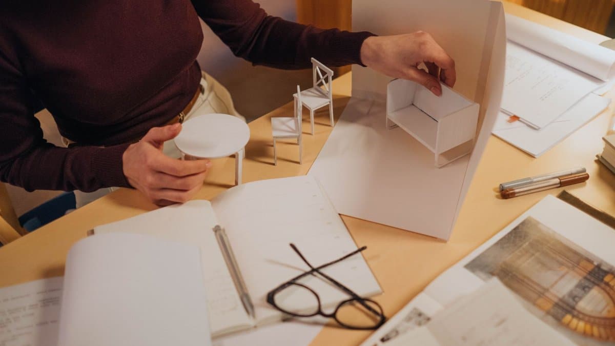 Architect working on miniature furniture models in a creative workspace. Focus on handmade design process.