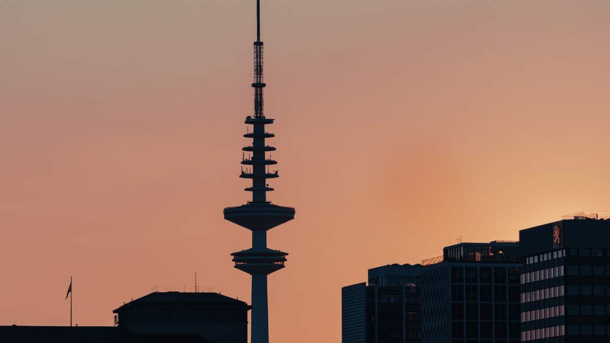Silhouetted view of a city skyline featuring a TV tower at sunset, exuding urban serenity.