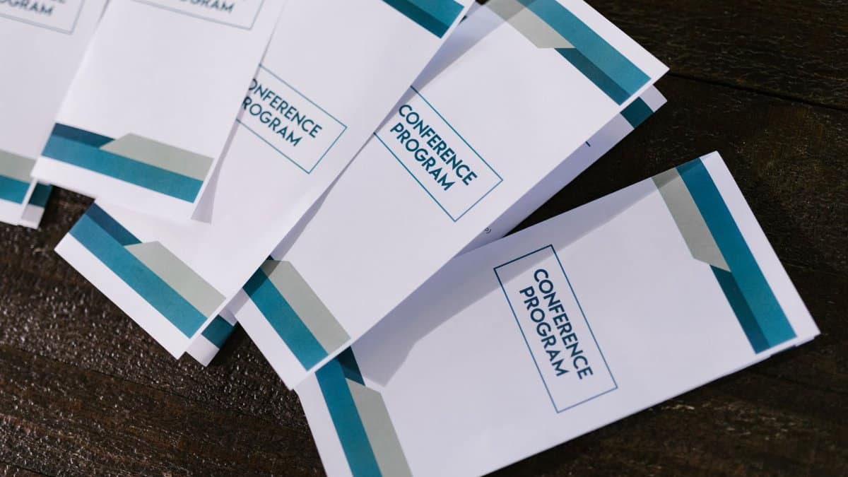 Close-up of neatly arranged conference program pamphlets on a wooden surface, suitable for professional and business settings.
