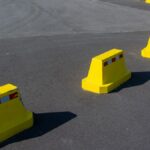 Row of bright yellow traffic barriers on an empty asphalt road.