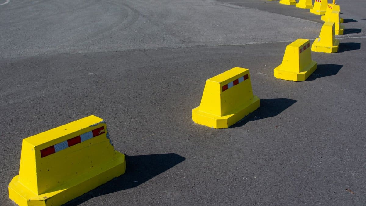 Row of bright yellow traffic barriers on an empty asphalt road.