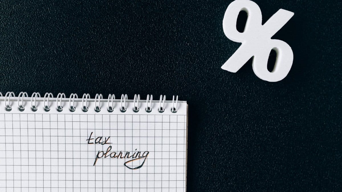 A notebook with 'tax planning' written on a grid paper next to a percent symbol on a black background.