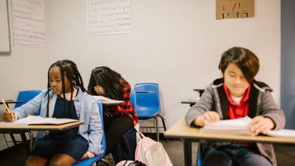 Three students in a classroom, focusing on bullying prevention awareness.