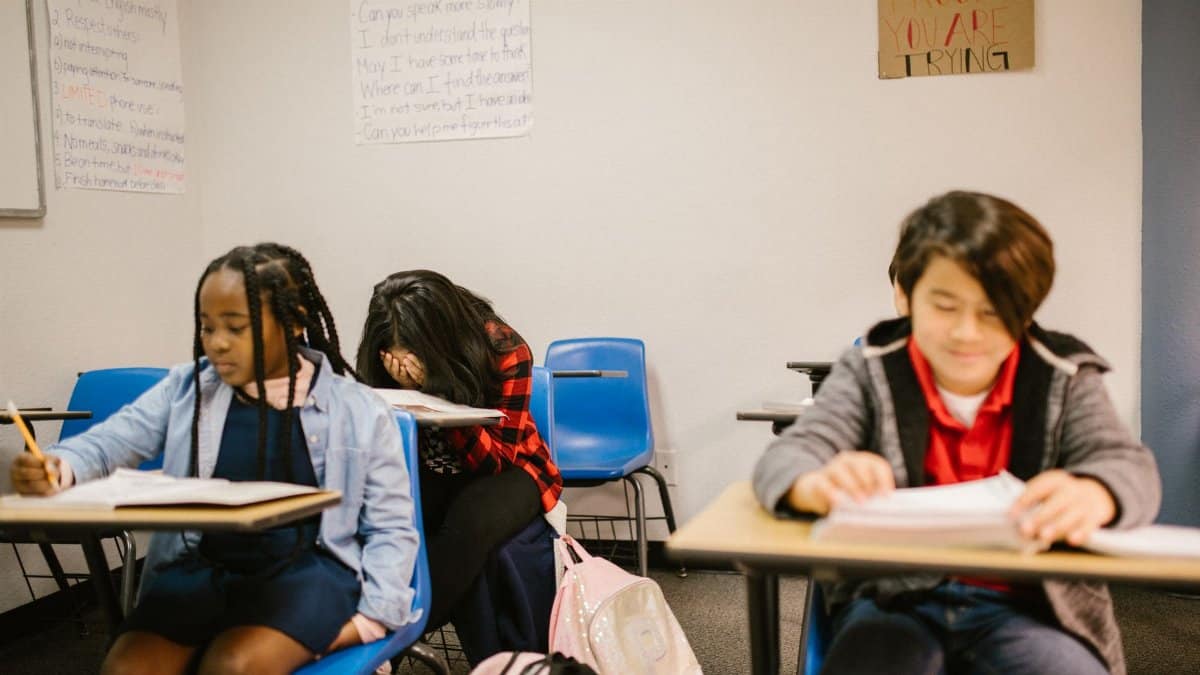 Three students in a classroom, focusing on bullying prevention awareness.