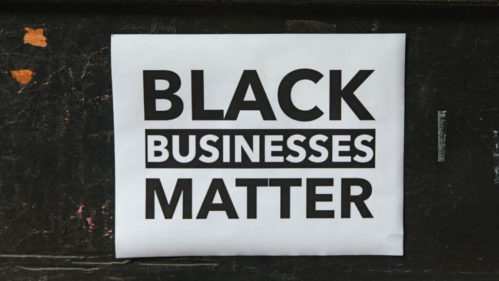 A poster advocating support for Black-owned businesses displayed on a textured wall.