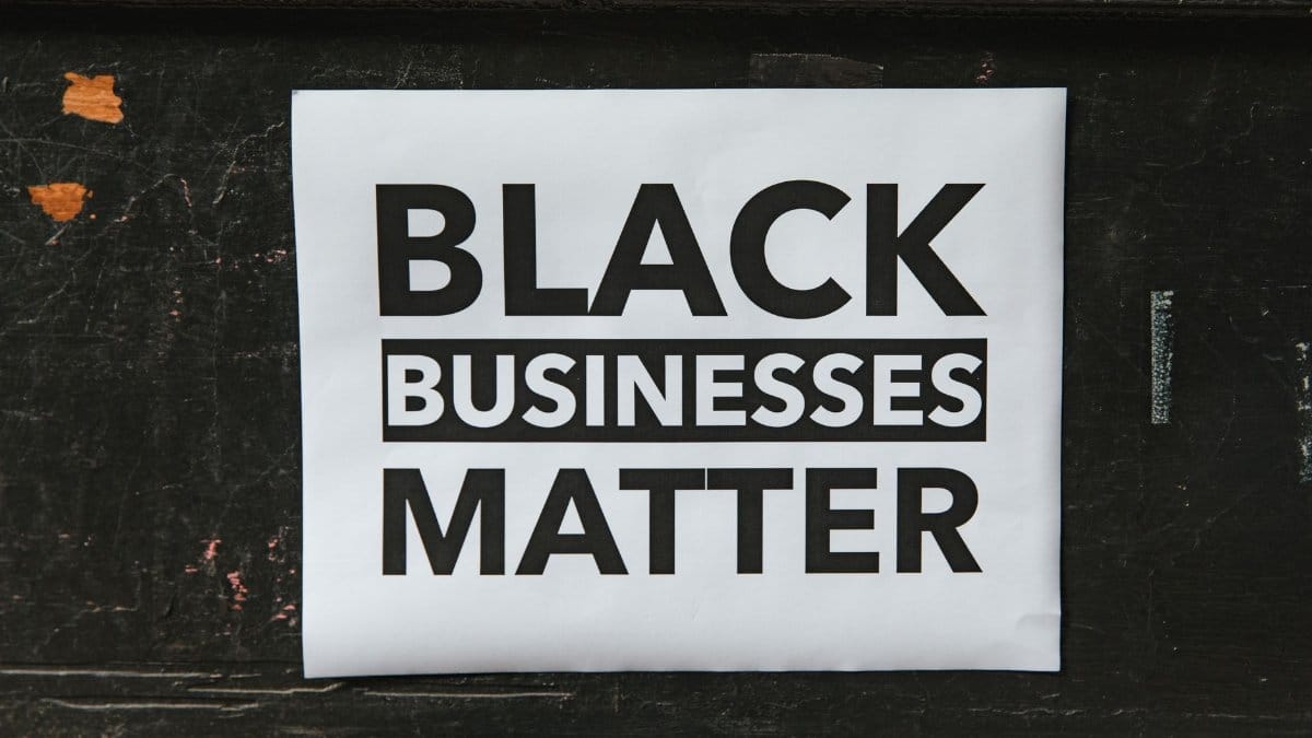 A poster advocating support for Black-owned businesses displayed on a textured wall.