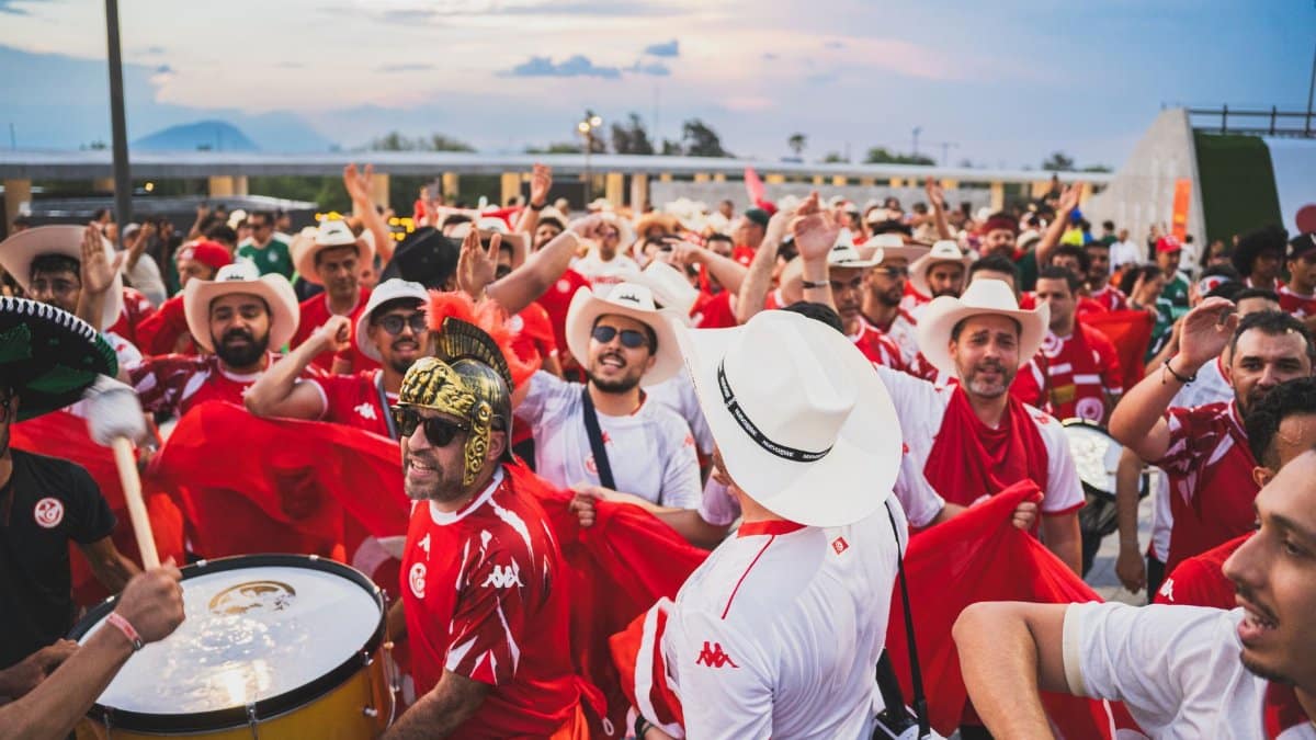 Crowd of passionate soccer fans in red and white outfits celebrating outdoors together.