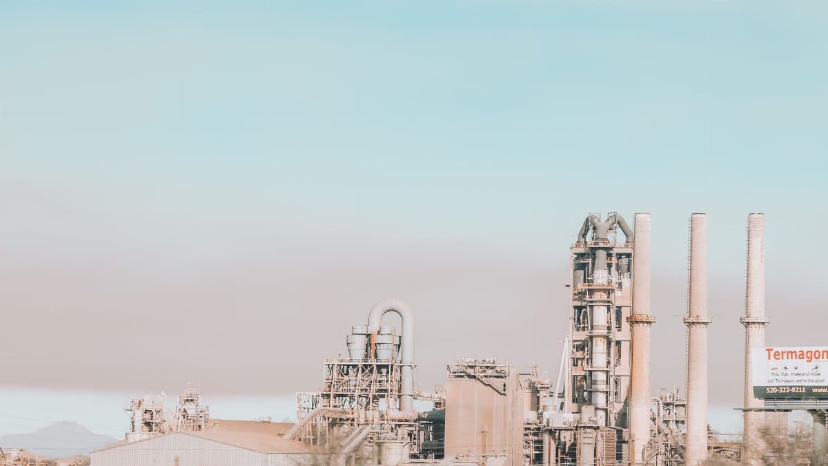 Power plant with similar stone chimneys and pipes near construction under colorful sky in city