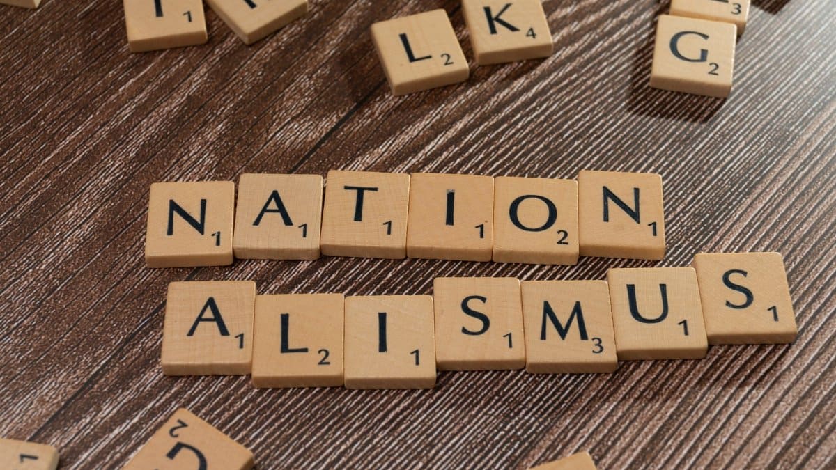 Scrabble tiles spelling 'Nationalismus' on a wooden surface, emphasizing patriotism and language concepts.