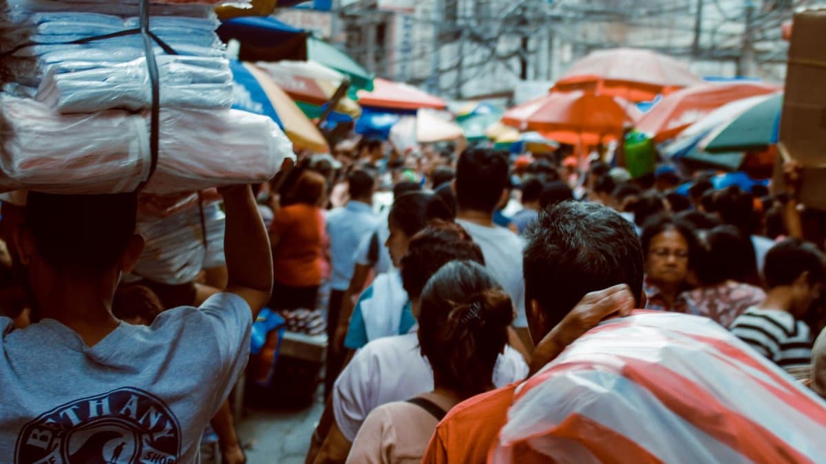 A crowded street market scene in Manila, showcasing vibrant local life under colorful umbrellas.