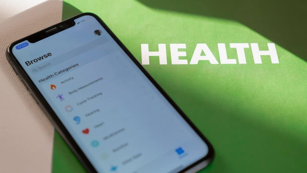 Close-up of a smartphone displaying a health app on a green surface with 'HEALTH' text.