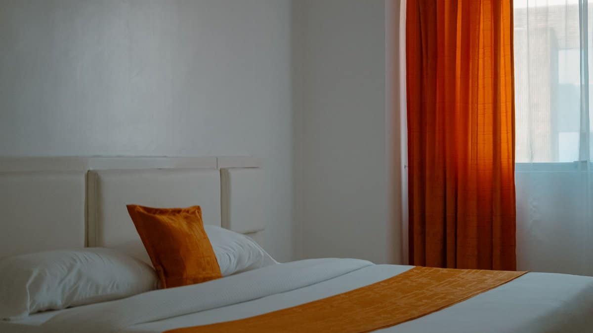 Warm and inviting hotel room with orange curtains and bedding creating a cozy ambiance.