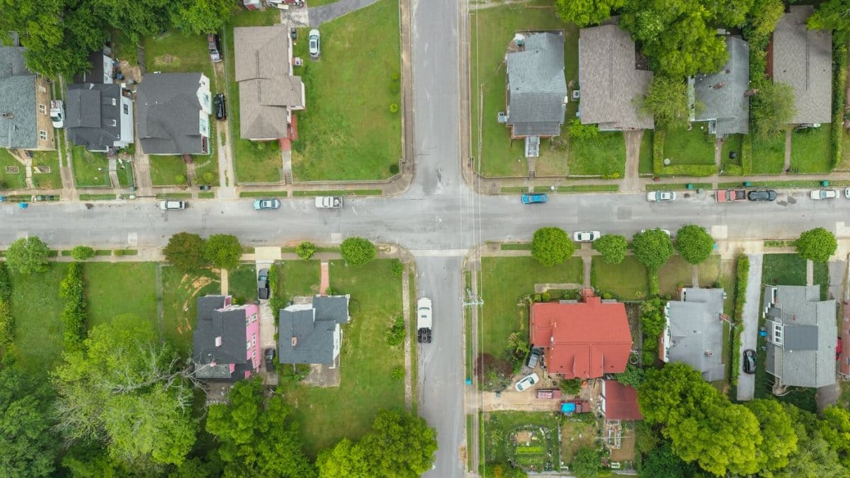 Aerial photo capturing an intersection in a suburban neighborhood with houses and greenery.