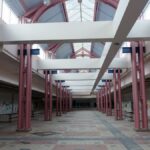 Desolate interior of an abandoned shopping mall with graffiti-covered walls.