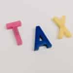 Colorful plastic letters spelling tax on a clean white background.