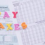 Close-up of U.S. tax forms with colorful 'PAY TAXES' letters emphasizing financial deadlines.