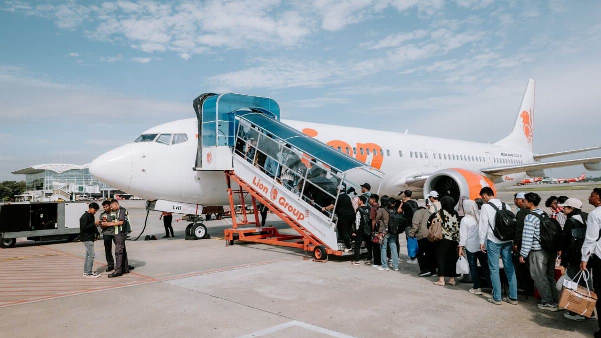 Travelers line up to board a Lion Air airplane at Medan Airport, Indonesia, during a sunny day.
