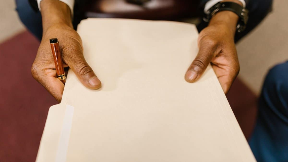 A business professional with a suit holding a legal folder and pen, indicating formal paperwork handling.