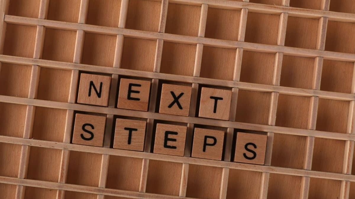 Flat lay of wooden letter blocks spelling 'Next Steps', inspiring progress and motivation.