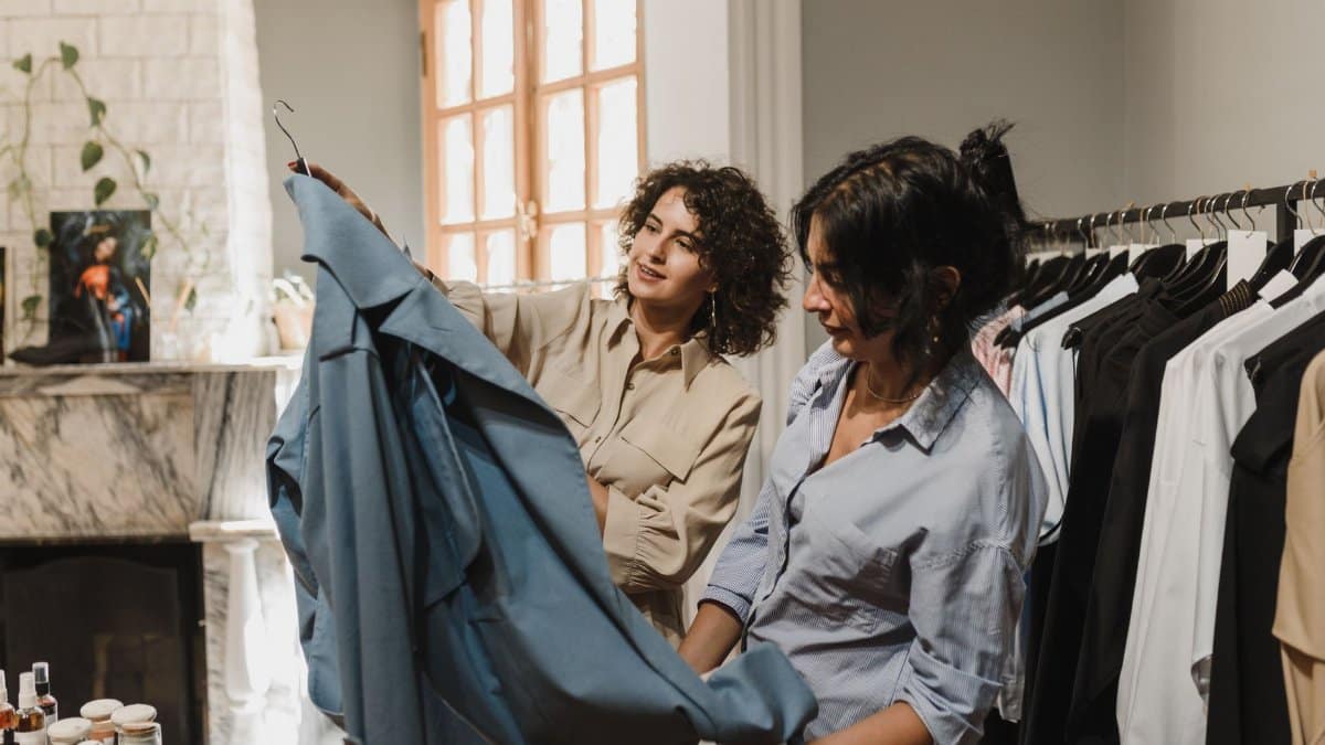 Two women shopping and exploring a variety of clothes in an elegant boutique.