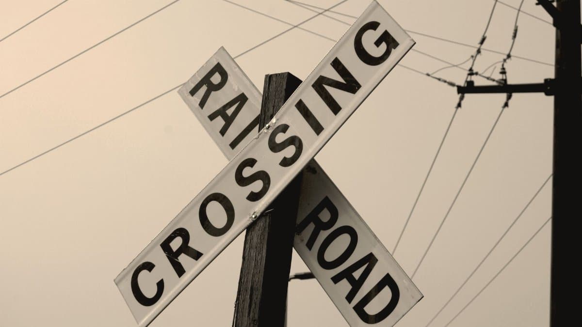 Low angle shot of a railroad crossing sign with electric wires in the evening sky.