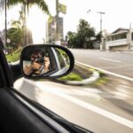 Photographer captures journey reflection on the road in a car side mirror.