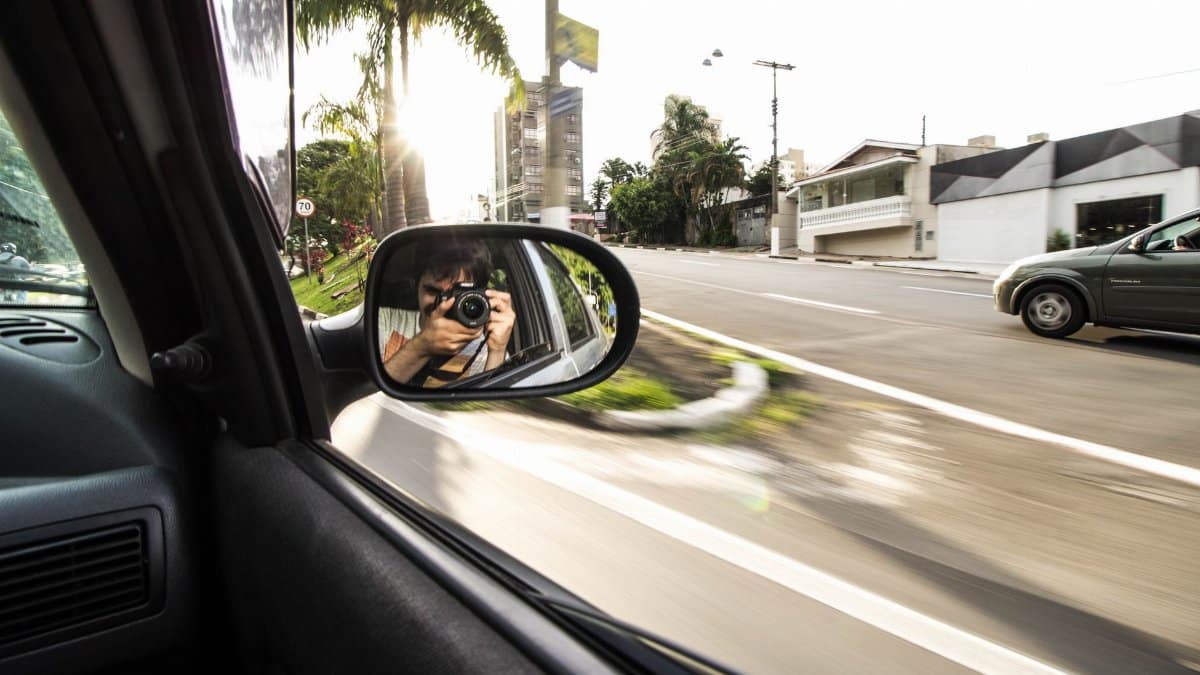Photographer captures journey reflection on the road in a car side mirror.