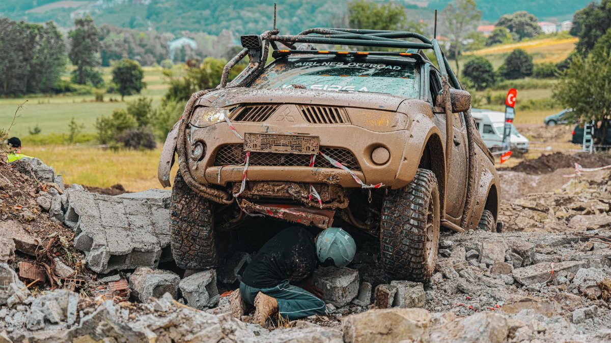 A 4x4 vehicle tackles a rocky off-road trail with a driver maneuvering through challenging obstacles.