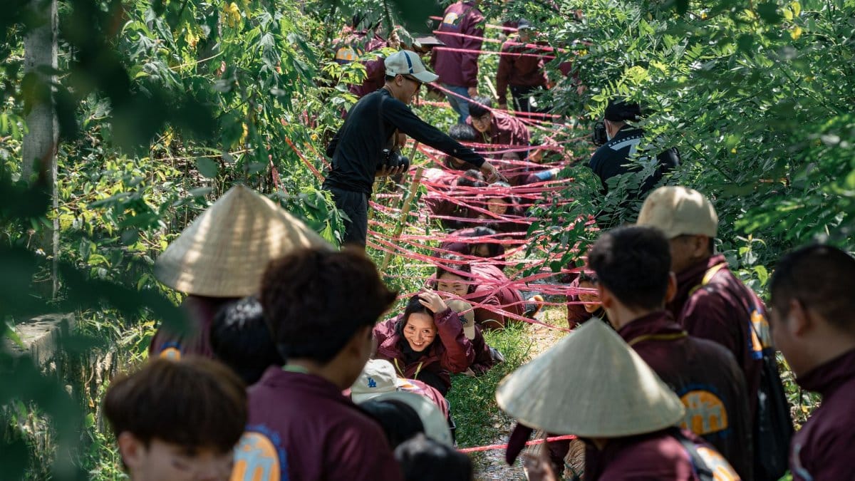 Participants navigate obstacle course in lush forest during adventure event.