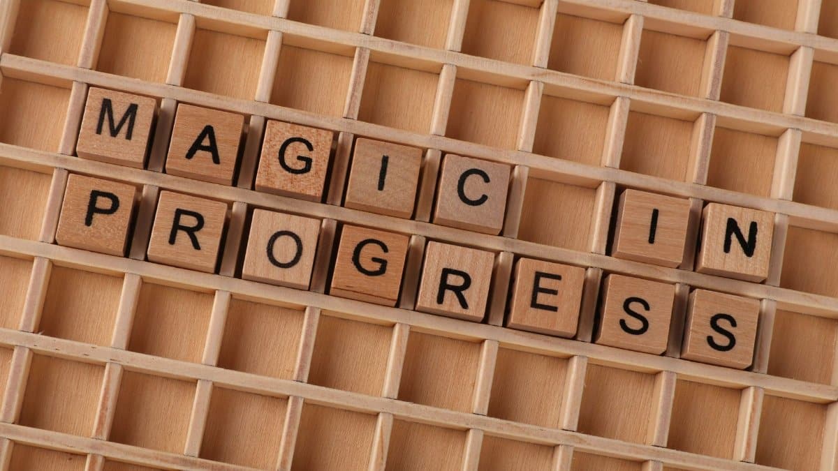 Wooden letter blocks arranged to spell 'Magic in Progress' on a grid.
