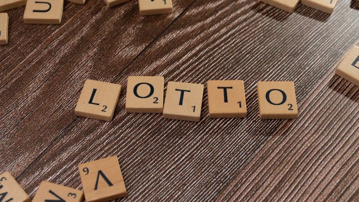 Scrabble tiles spelling 'LOTTO' on a wooden table surface, symbolizing chance and gaming.
