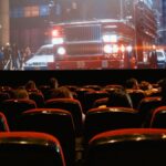 People seated in a cinema watching a movie on a large screen.