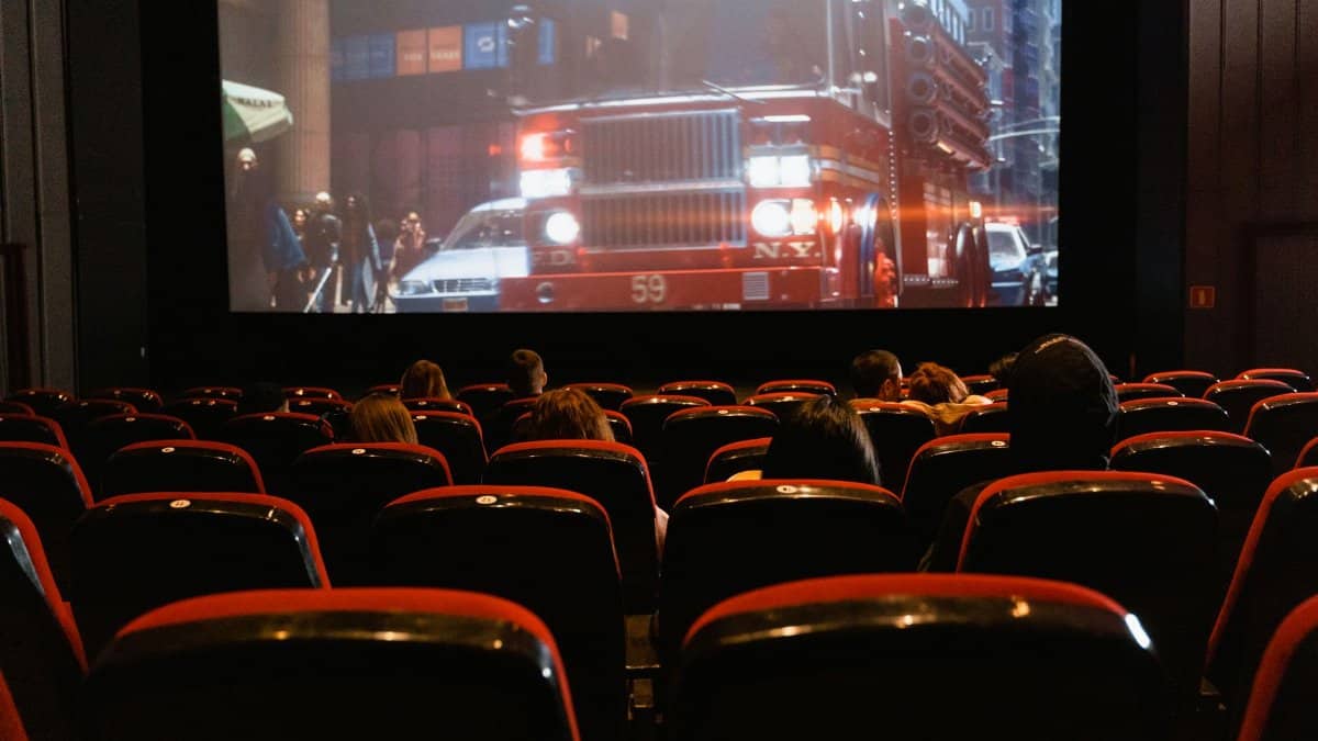 People seated in a cinema watching a movie on a large screen.