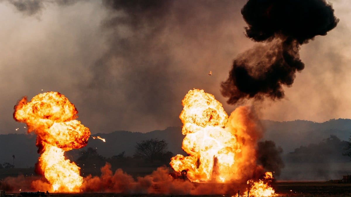 Intense explosion scene with billowing fire and dark smoke against an outdoor landscape.