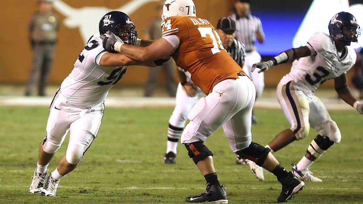 Athletes in action during an American football game on a grassy field.