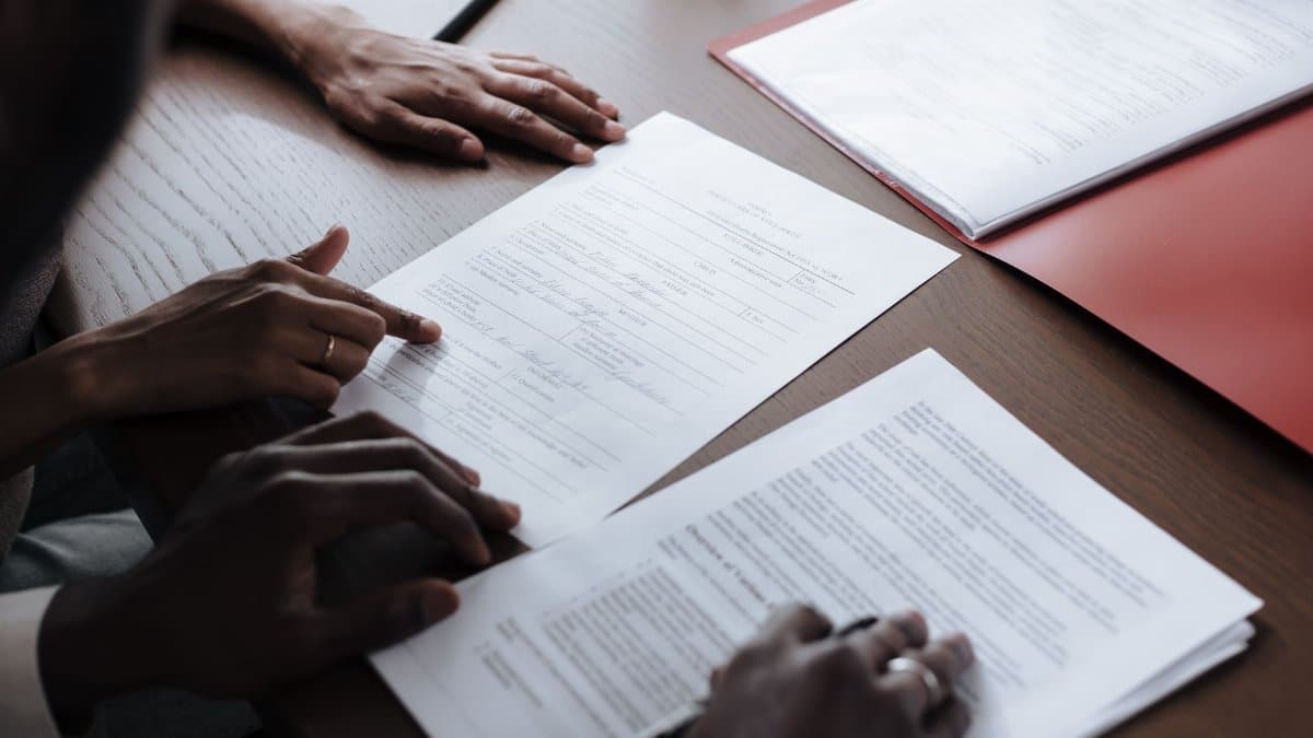 Two individuals reviewing and signing official documents in an indoor setting.