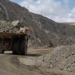 A large mining truck transporting rocks in an open-pit quarry, showcasing industrial machinery.