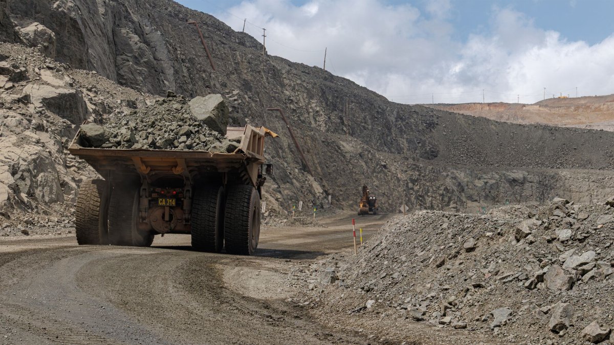 A large mining truck transporting rocks in an open-pit quarry, showcasing industrial machinery.